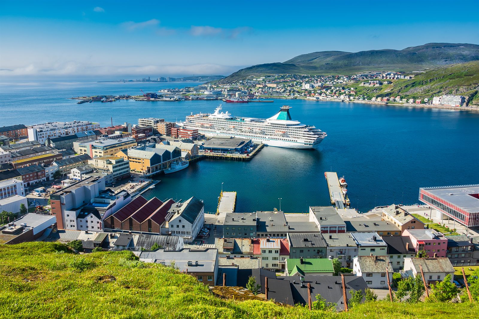Cruise ship docked in the harbor of a small town in Arctic Norway under a summer sky
